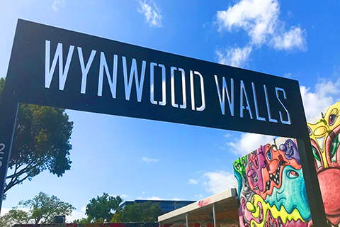 A stock photo of the sign in front of Wynwood Walls in the Wynwood Art District of Miami, Florida.